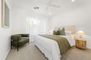 a white bedroom with a bed and a chair at The Grape Escape Location and style on Shiraz Trail in McLaren Vale