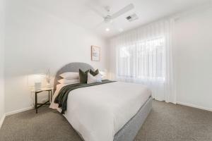 a white bedroom with a bed and a window at The Grape Escape Location and style on Shiraz Trail in McLaren Vale