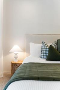 a bed with green and white pillows and a lamp at The Grape Escape Location and style on Shiraz Trail in McLaren Vale