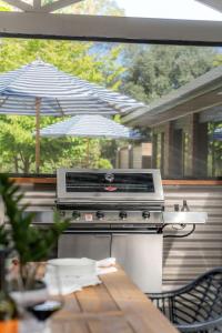 a grill on a patio with a table and an umbrella at The Grape Escape Location and style on Shiraz Trail in McLaren Vale