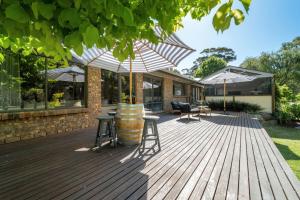 a wooden deck with a barrel and chairs and umbrellas at The Grape Escape Location and style on Shiraz Trail in McLaren Vale
