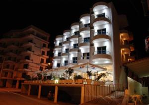 un gran edificio blanco con una fachada iluminada por la noche en Arel Hotel en Sarandë