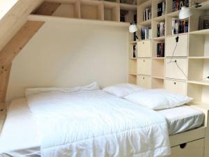 um quarto com uma cama branca e prateleiras de livros em Gwez-Roz - Villa en bois Perros-Guirec em Perros-Guirec