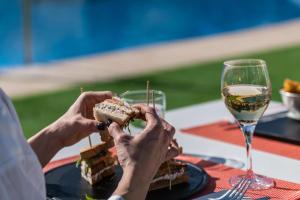 een persoon met een sandwich en een glas wijn bij THB Maria Isabel - Adults Only in Playa de Palma