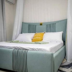 a blue and white bed with an orange pillow on it at Lovana apartments and hotel in Gulu