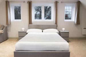 a bedroom with a large bed and three windows at KingsHouse In Cheam Village in Cheam