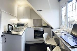 KingsHouse In Cheam Village في Cheam: مطبخ مع جهاز كمبيوتر محمول على منضدة