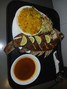 a tray with a plate of fish and a bowl of soup at Lovana apartments and hotel in Gulu