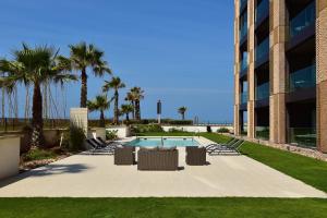une piscine avec des chaises longues et un bâtiment dans l'établissement Pestana Casablanca, Seaside Suites & Residences, à Casablanca