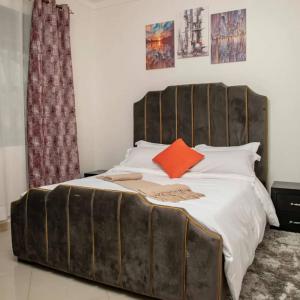 a bedroom with a large bed with an orange pillow at Lovana apartments and hotel in Gulu