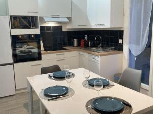 a kitchen with a table with plates and wine glasses at L'hibiscus maison 4 personnes in Dolus-d'Oléron +6 photos