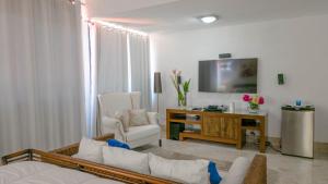 a living room with a white couch and a tv at Casa de Campo 4-BR Retreat: Pool, Jacuzzi, Sauna, Chef & Maid in La Romana