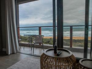 a room with a balcony with a view of the ocean at White Sands Self-catering units in Wilderness