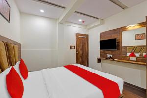 1 dormitorio con 1 cama roja y blanca y TV en OYO Flagship Hotel Swagat Inn, en Ahmedabad