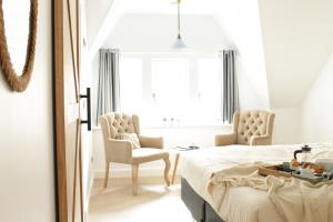 a bedroom with a bed and two chairs and a window at D’oude Dune in Nieuwpoort