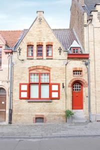 un bâtiment en briques avec des fenêtres rouges et une porte rouge dans l'établissement D’oude Dune, à Nieuport