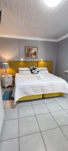 1 dormitorio con 1 cama grande y cabecero amarillo en Be My Guest, en Alberton