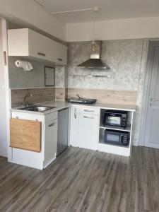 La cuisine est équipée de placards blancs, d'un évier et d'un four micro-ondes. dans l'établissement Mignon studio au cœur de Mèze, à Mèze