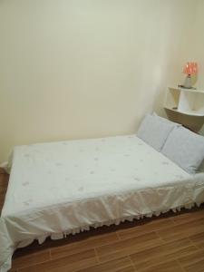 a bed with white sheets and pillows in a room at bucana traveler's inn in Guinisiliban