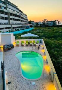 une piscine avec des tables et des chaises et un bâtiment dans l'établissement White&Blue luxury suites, à Ialyssos