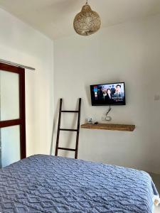 1 dormitorio con 1 cama y TV en la pared en Saellahouse, en Gili Trawangan