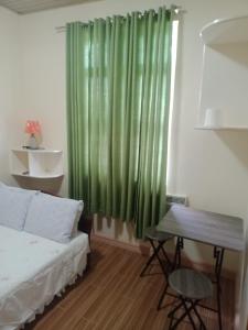 1 dormitorio con 1 cama y cortina verde en bucana traveler's inn, en Guinisiliban