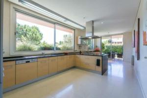 una grande cucina con armadi gialli e una grande finestra di Villa Atlantic Pearl - Luxury villa located in a Quinta do Lago
