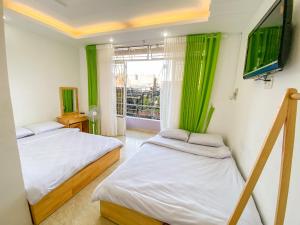 a bedroom with two beds and a window with green curtains at HẢI ANH in Da Lat