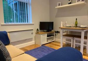 Una sala de estar con un sofá y una mesa con televisión. en Apartment 2, 11 The Beach - Ground floor beachfront apartment - Ocholo Villas, en Filey