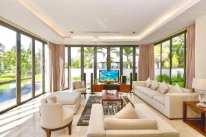 a living room with white furniture and large windows at Dreamy Beach Villas And Resort in Danang