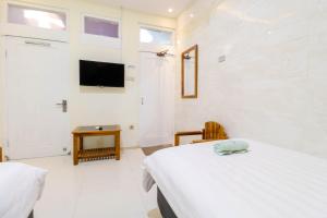 Hotel Safara Yogyakarta في يوغياكارتا: غرفة نوم بسريرين وتلفزيون على الحائط