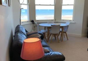 Una sala de estar con un sofá de cuero y una mesa. en Apartment 5, 11 The Beach - Spectacular views of the bay, en Filey