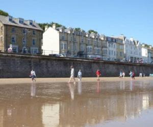 un grupo de personas caminando por la playa en Apartment 5, 11 The Beach - Spectacular views of the bay, en Filey