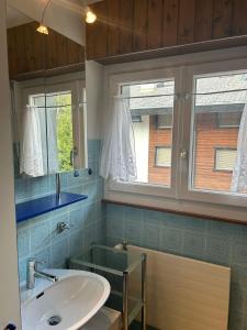 ein Badezimmer mit einem Waschbecken und einem Spiegel sowie zwei Fenstern in der Unterkunft Ramuge COSY & MOUNTAINS apartments in Veysonnaz