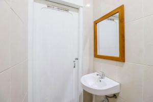 Baño blanco con lavabo y espejo en Hotel Safara Yogyakarta en Yogyakarta