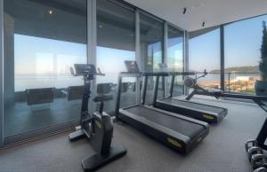 a gym with three treadmills in a building with windows at Sea Star Budva in Budva