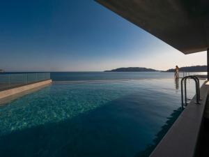 a woman standing in a swimming pool overlooking the water at Sea Star Budva in Budva