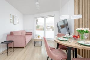 a living room with a table and pink chairs at Stylish Apartment with Balcony and Garage in Świnoujście by Renters in Świnoujście
