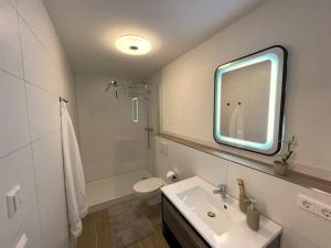 een badkamer met een wastafel, een toilet en een spiegel bij Gästehaus Stoll in Filderstadt