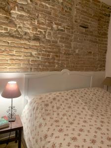 1 dormitorio con cama y pared de ladrillo en Casina Centotrecento-Romantic & Quite Apartment-, en Bolonia