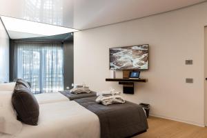 San Barbato Resort Spa & Golf في Lavello: غرفة نوم بسريرين وتلفزيون على الحائط