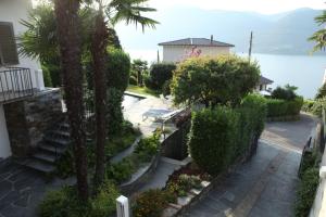 a house with a palm tree and stairs next to the water at Casa Ramerino in Brissago