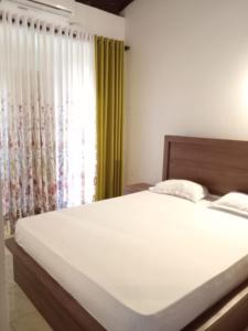 Un dormitorio con una gran cama blanca y una ventana en Jayawardana House, en Matara