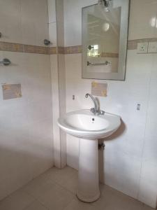 y baño con lavabo blanco y espejo. en Jayawardana House, en Matara