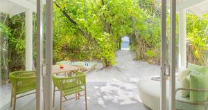 Habitación con porche con mesa y sillas. en RAAYA By Atmosphere - Premium All Inclusive with Free Transfers, en Raa Atoll