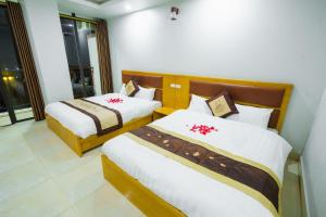 1 Schlafzimmer mit 2 Betten in Weiß und Braun in der Unterkunft UFJ HOTEL Sầm Sơn in Sầm Sơn