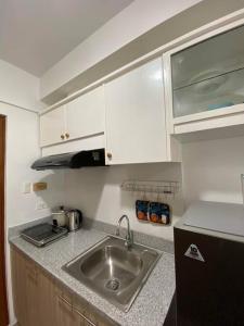een keuken met een wastafel en witte kasten bij Isabela 1 Mesavirre Residences in Bacolod +3 foto's