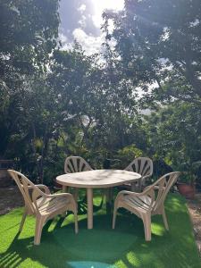 a white table and two chairs on the grass at La Piaule De Nessadiou in Bourail