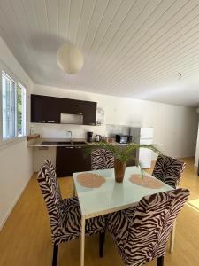 a dining room with a table and zebra chairs at La Piaule De Nessadiou in Bourail