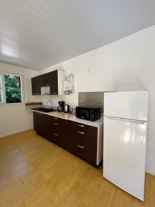 a kitchen with a white refrigerator and a wooden floor at La Piaule De Nessadiou in Bourail +11 photos